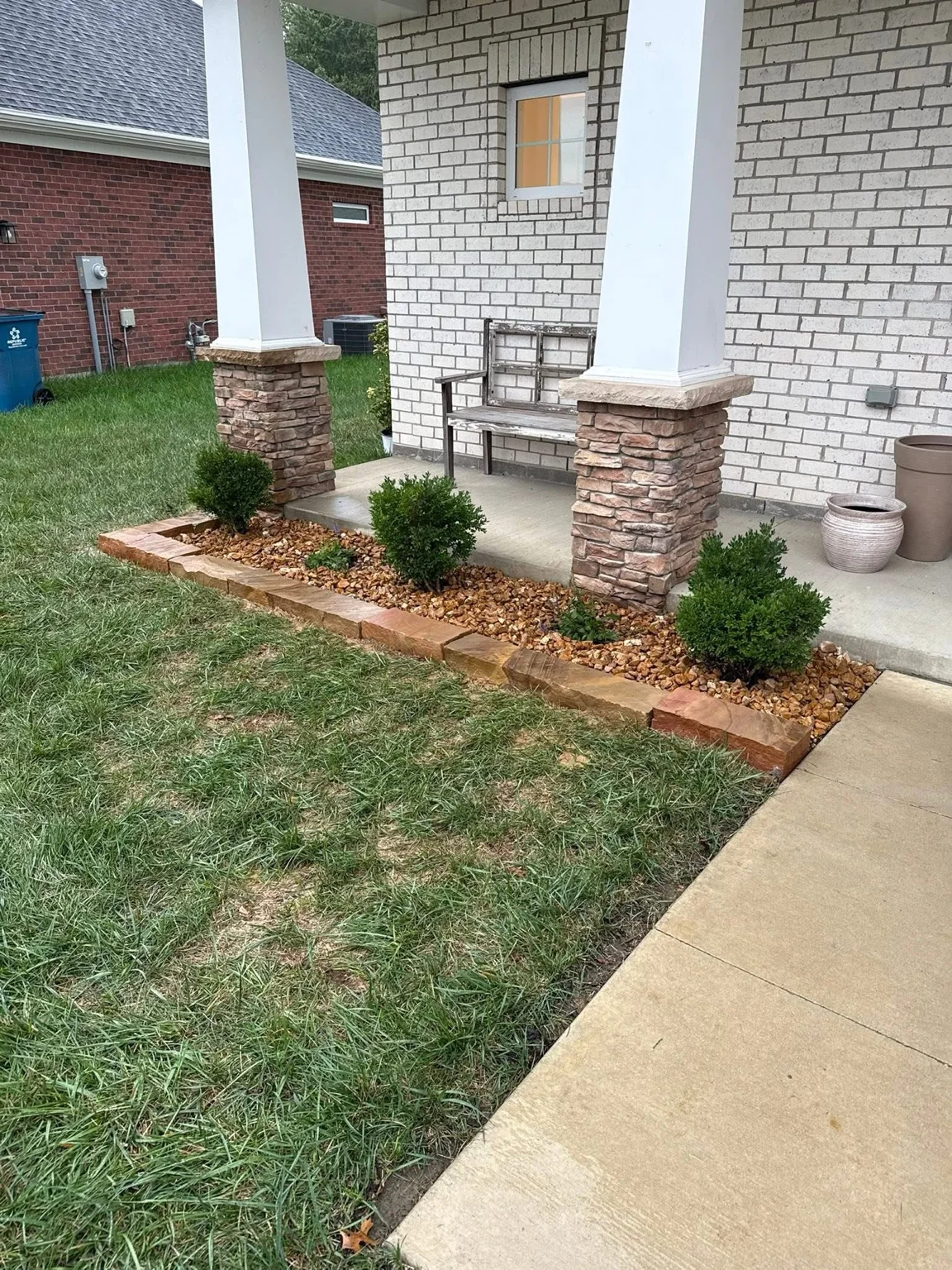 Front porch landscape bed with natural stone edging, decorative rock, and shrubs