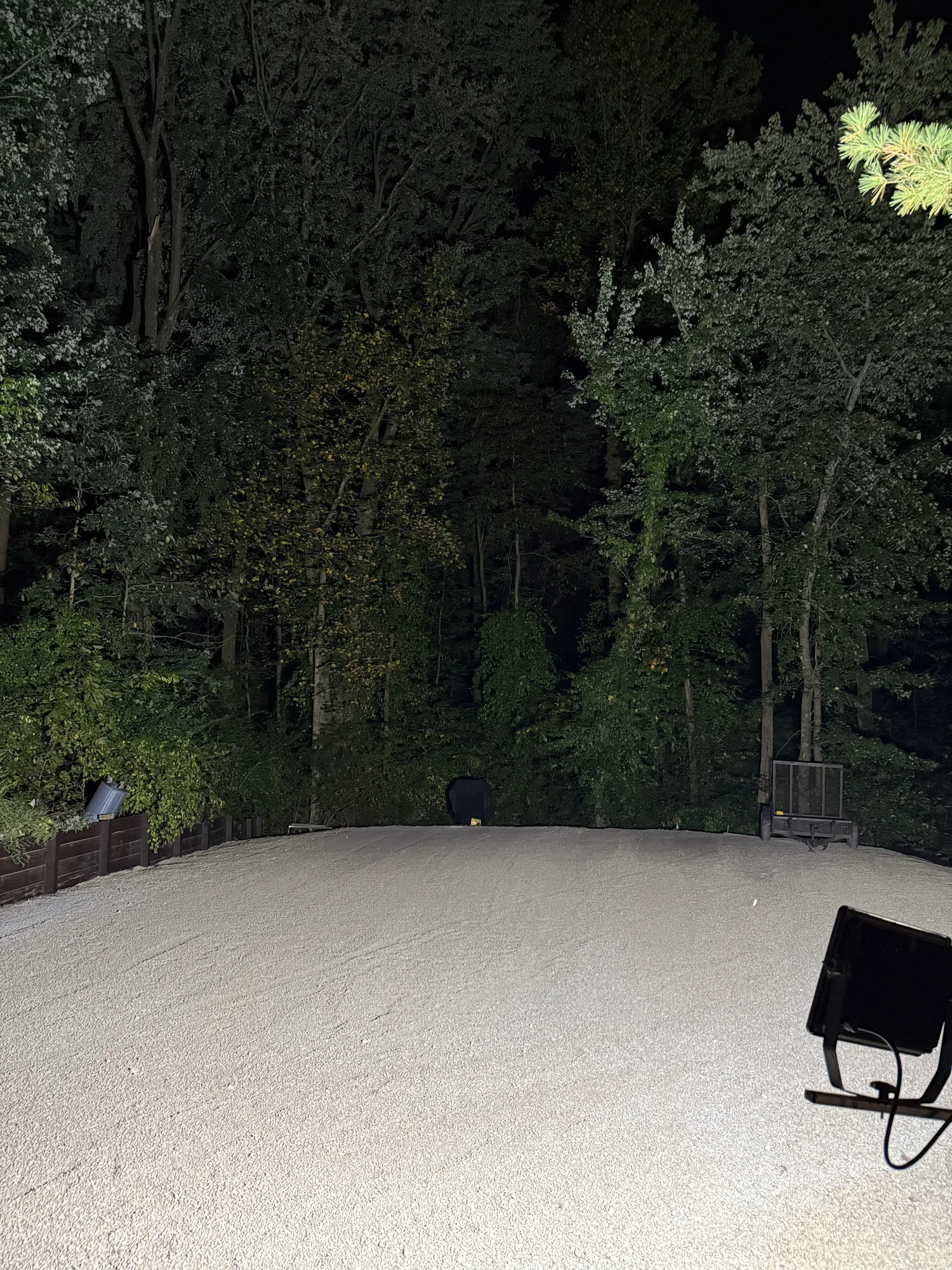 Newly installed and graded gravel pad beside a wooded property