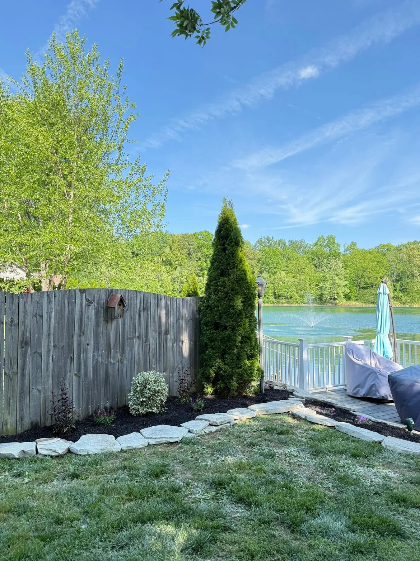 Lakefront landscape bed with natural stone edging, dark mulch, and new plantings