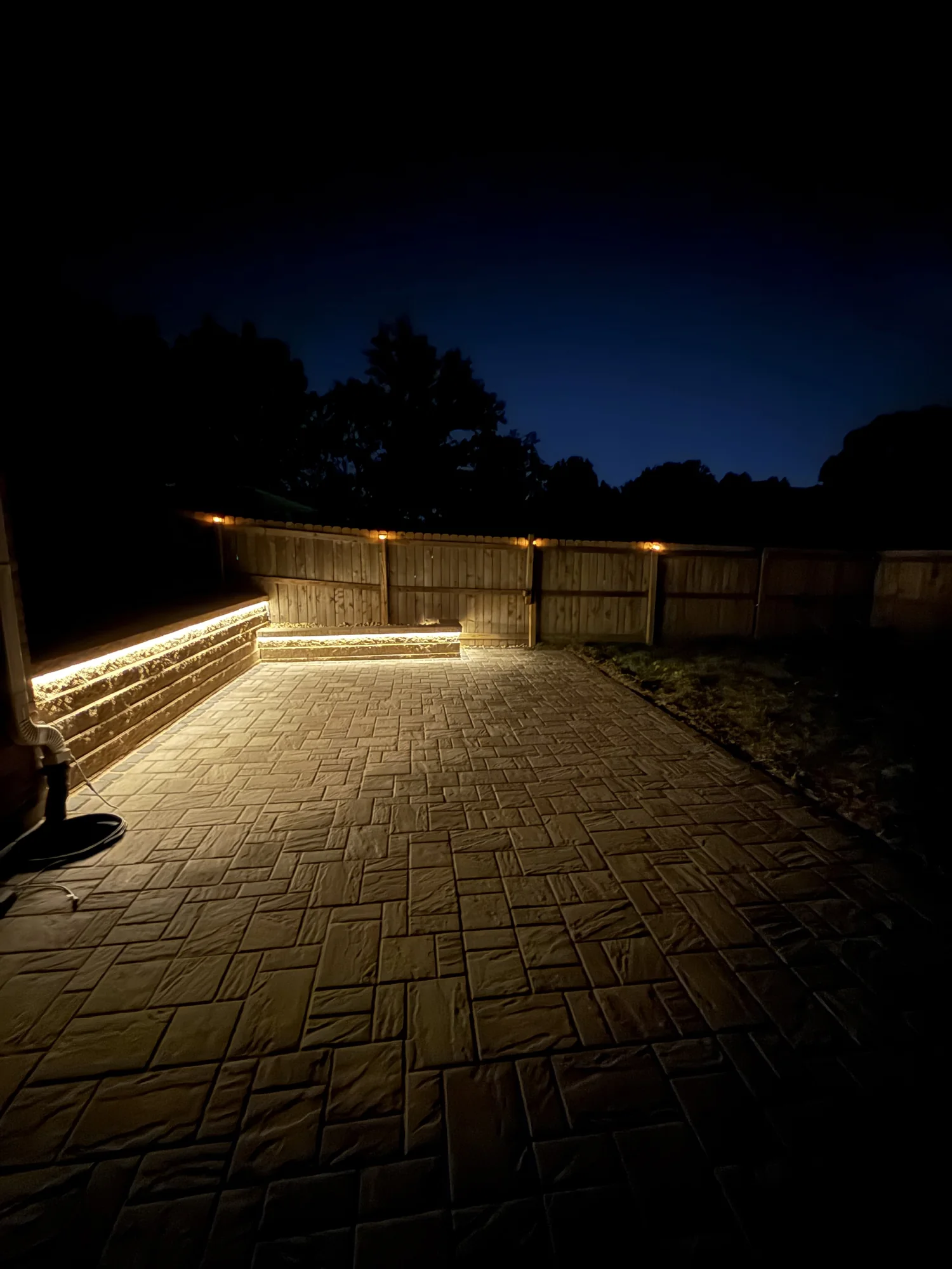 Completed paver patio and retaining wall illuminated at night